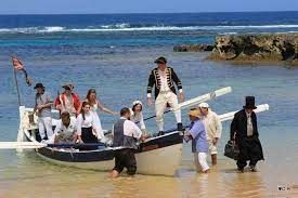 A group of people are standing on top of a boat in the water.