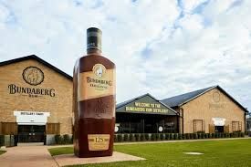 Giant Bundaberg Rum bottle statue in front of distillery buildings.