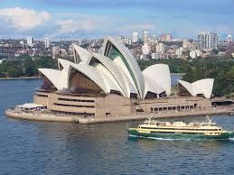 The sydney opera house is floating on top of a body of water next to a boat.