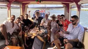 Group of people on a boat, celebrating, with an Australian flag in the background.