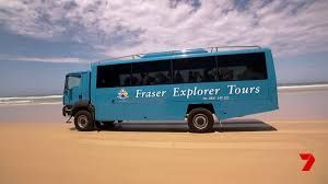 Light blue tour bus on a sandy beach, advertising