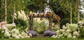 A garden path leads to a floral archway, surrounded by lush greenery and flowers.