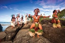 A group of people are dancing on rocks near the ocean.