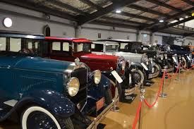 A row of old cars are lined up in a museum.
