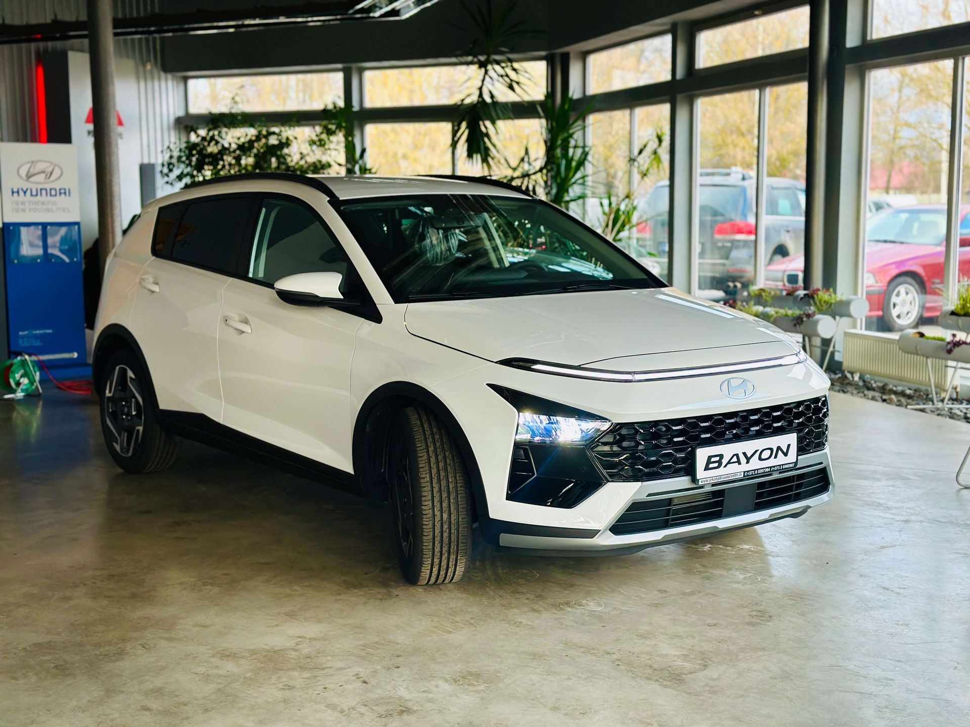 Autosalonā stāv sarkana mašīna.