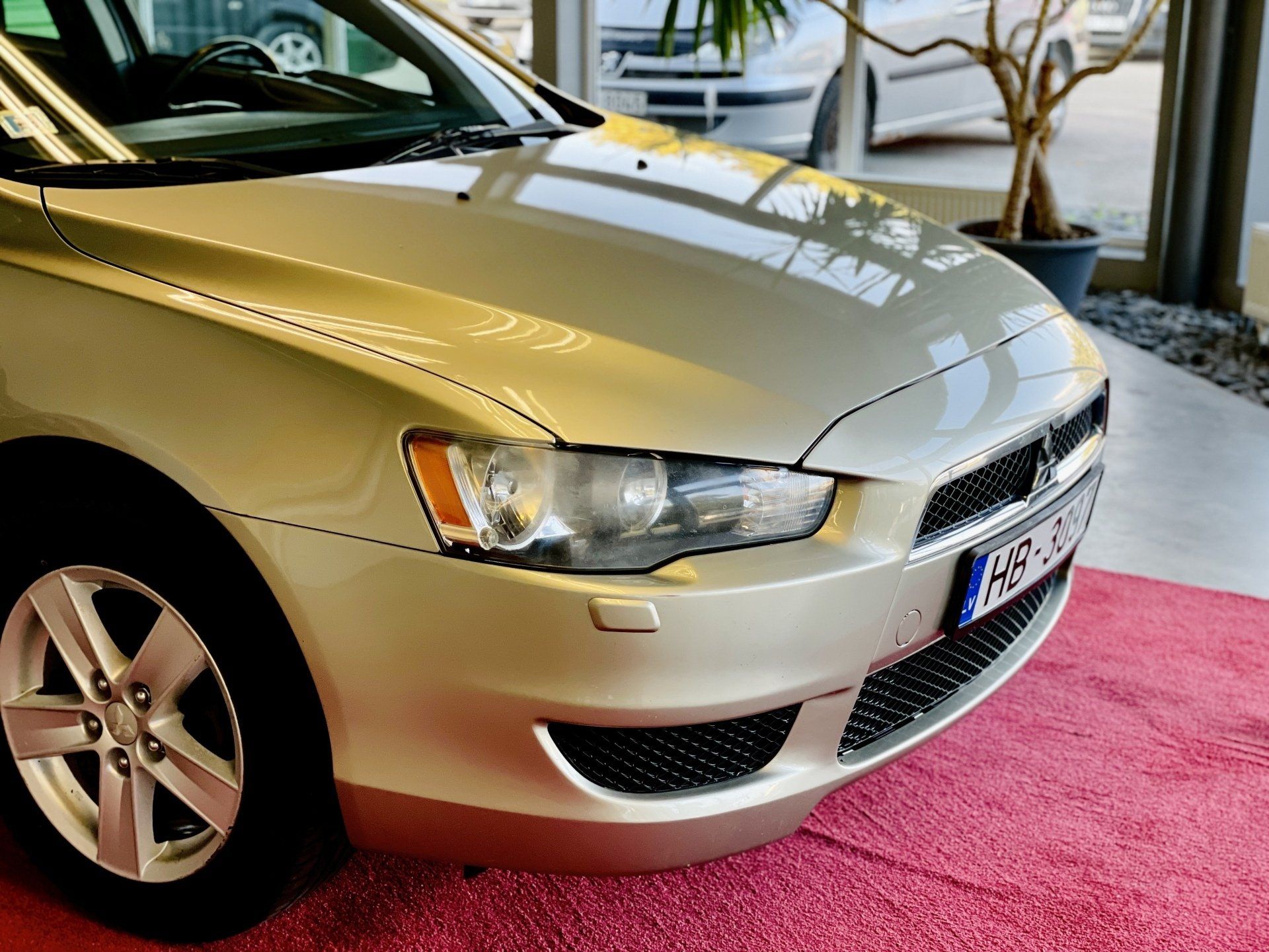 Sudraba automašīna ir novietota uz sarkanā paklāja izstāžu zālē