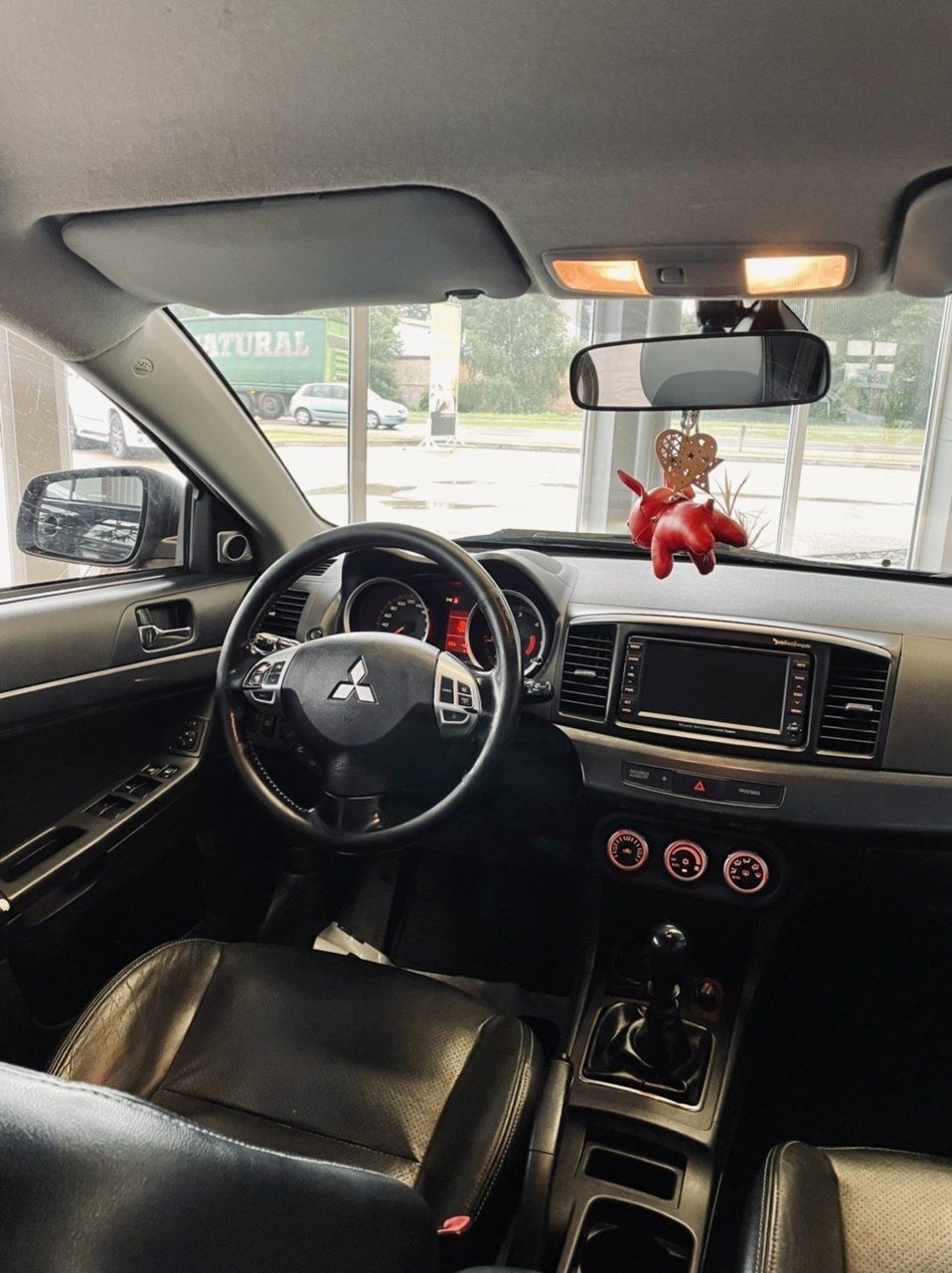 Mitsubishi lancera interjers ar izbāzni, kas karājās atpakaļskata spogulī.