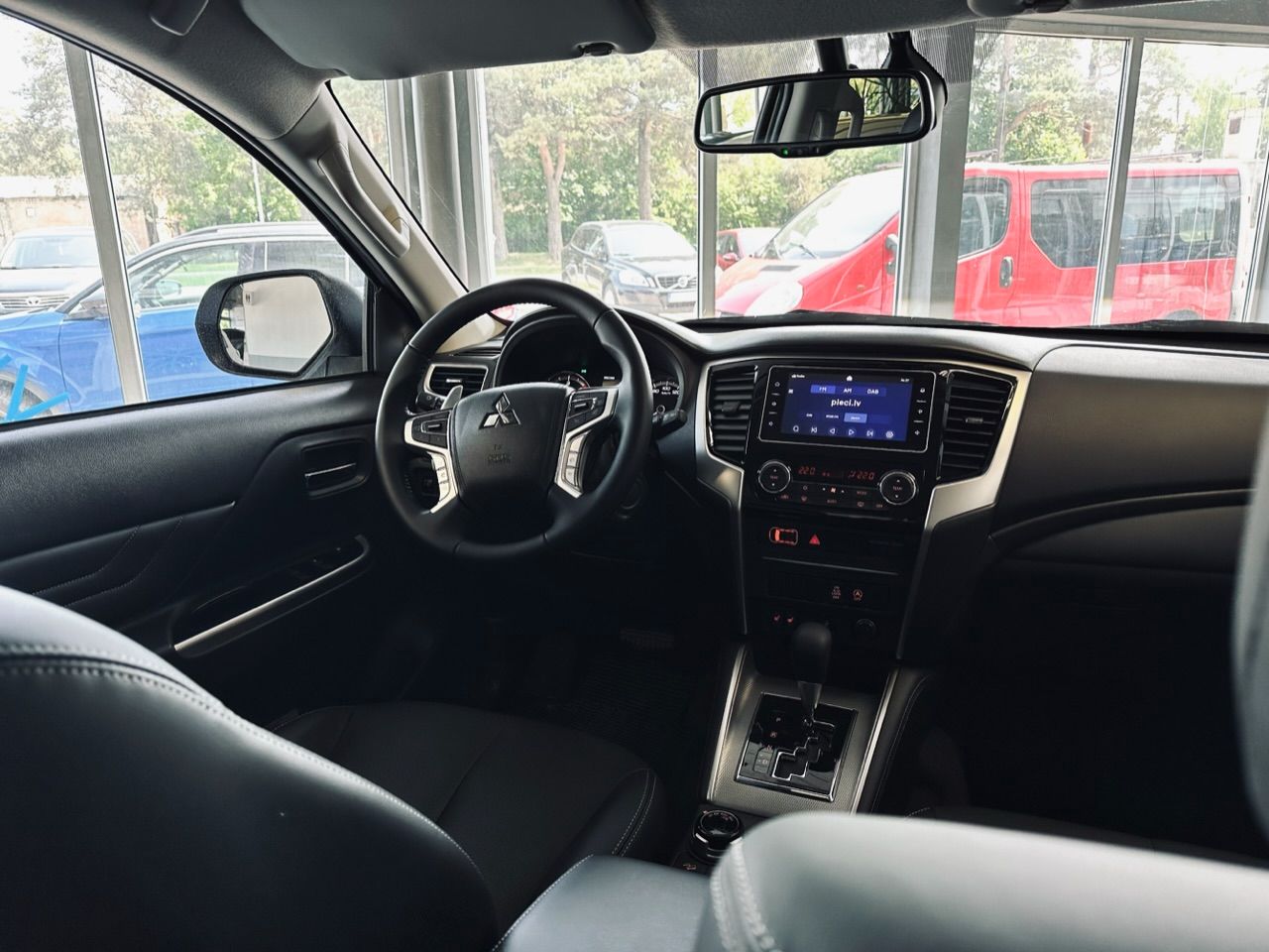 Automašīnas salons ar stūri un atpakaļskata spoguli.