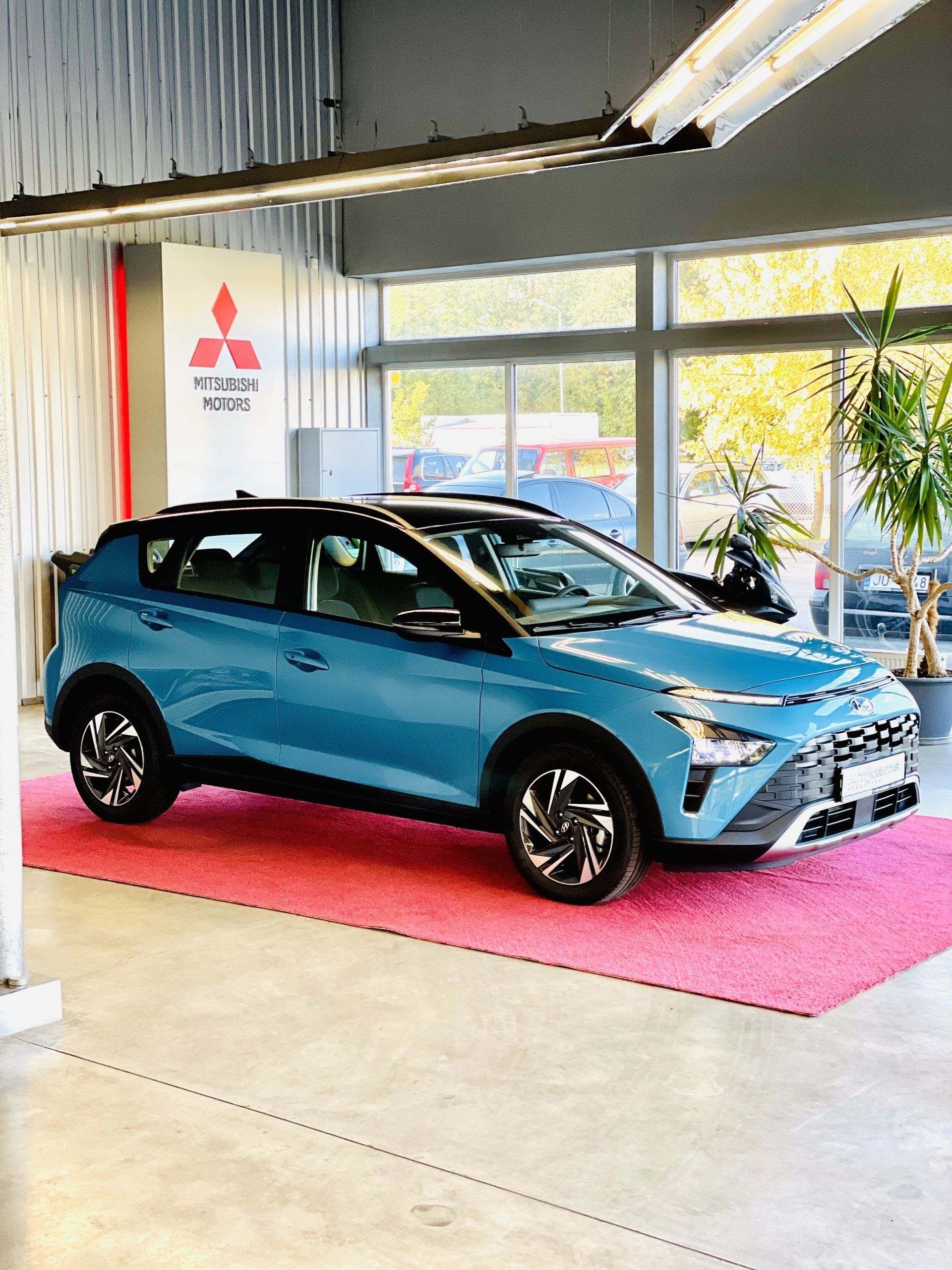 Zila mašīna stāv uz rozā paklājiņa salonā.