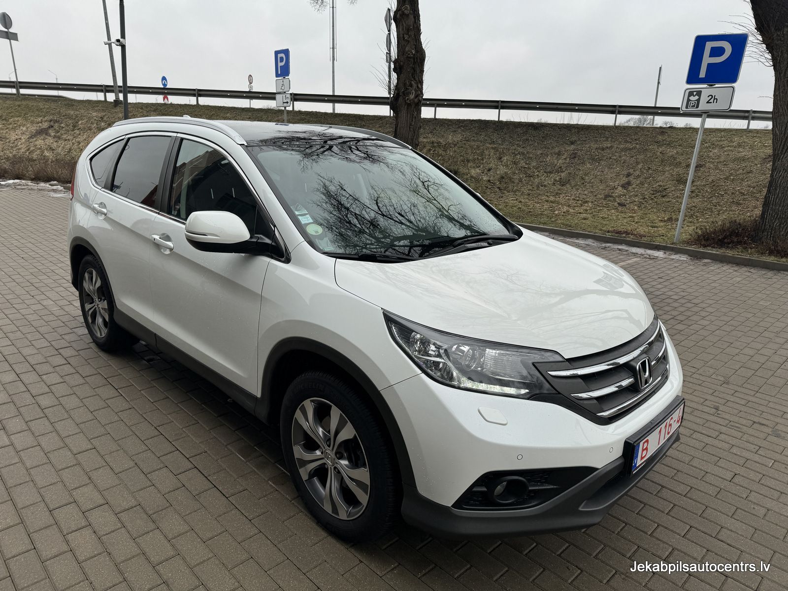 Stāvvietā stāv balta honda cr v.