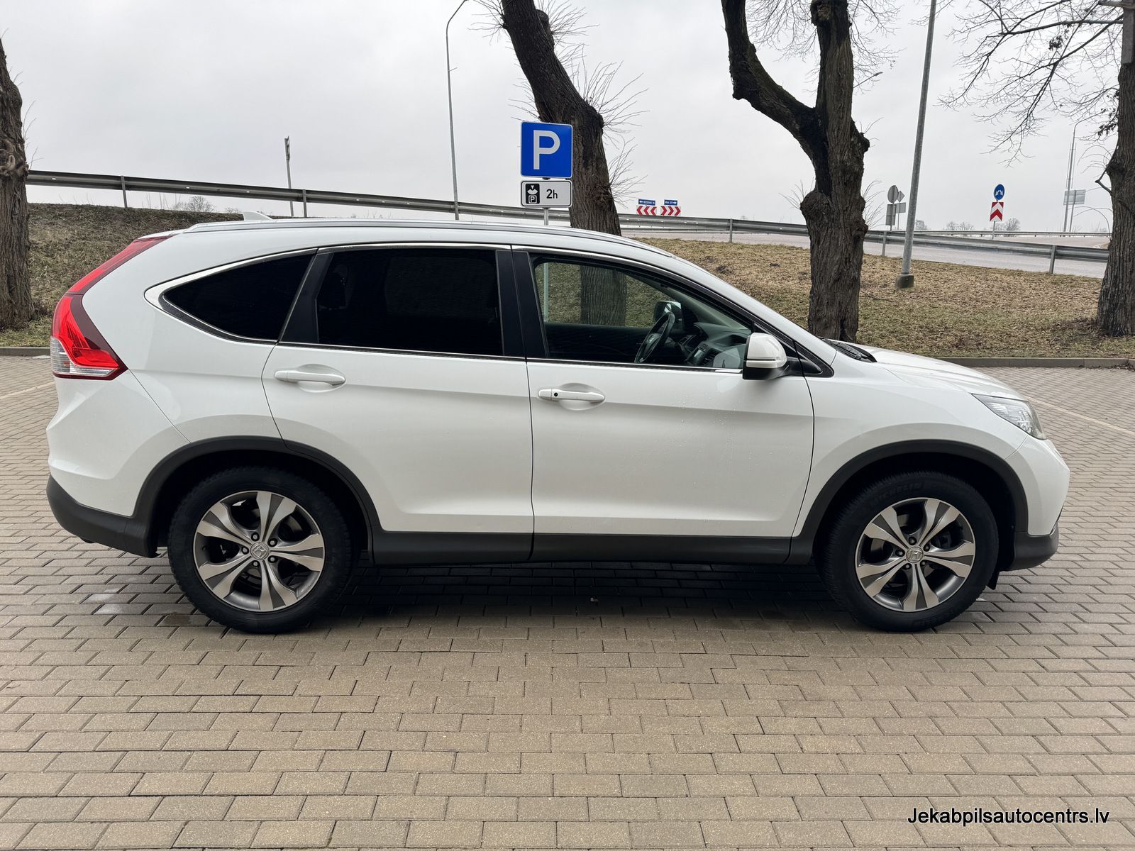 Stāvvietā stāv balta honda cr v.