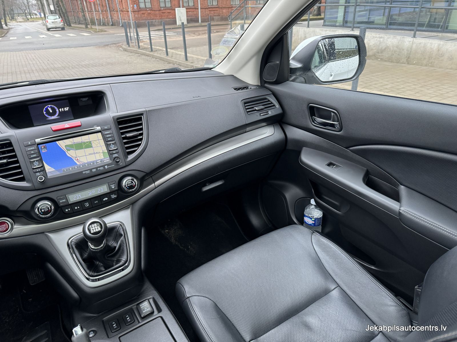 Automašīnas salons ar ūdens pudeli pasažiera sēdeklī.