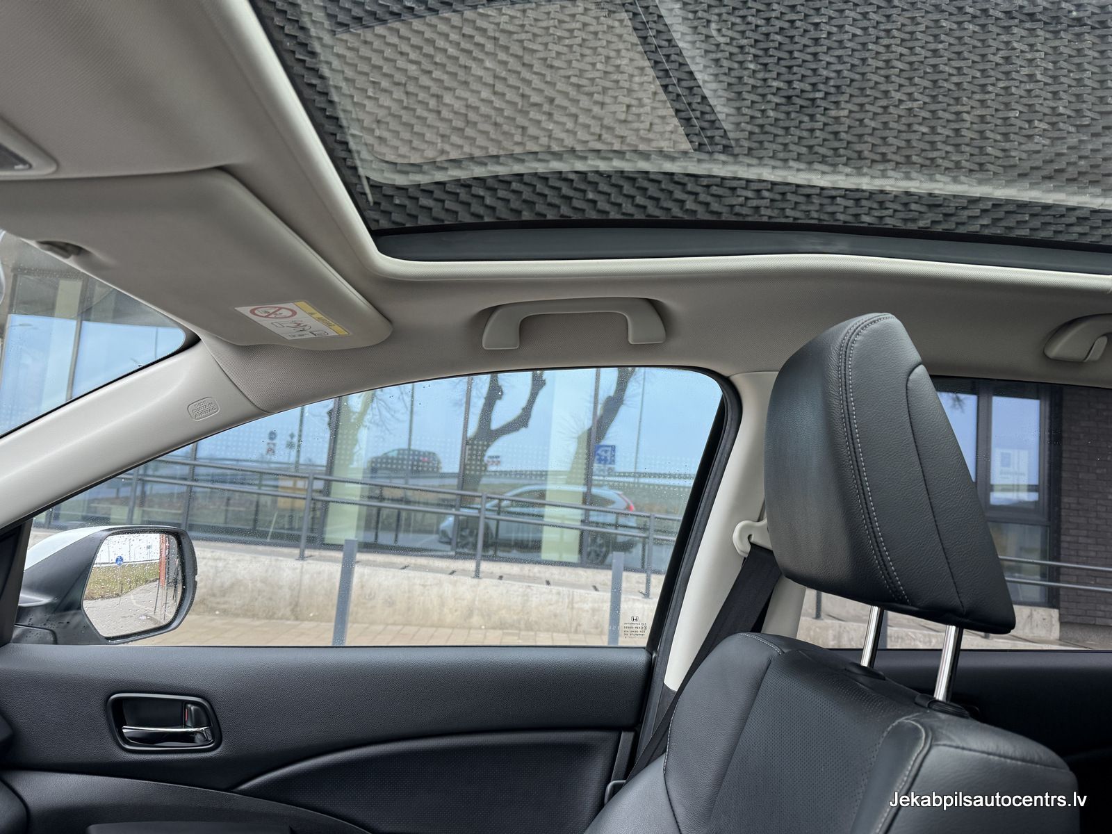 Automašīna ar jumta lūku ir novietota pie ēkas.