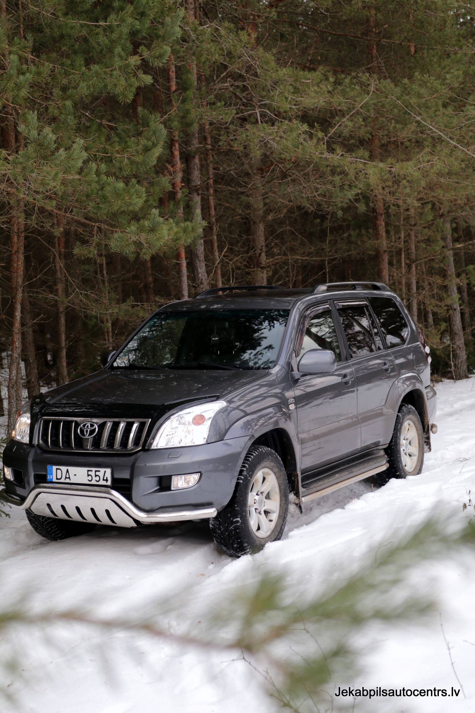 Pa sniegu mežā brauc toyota land cruiser.