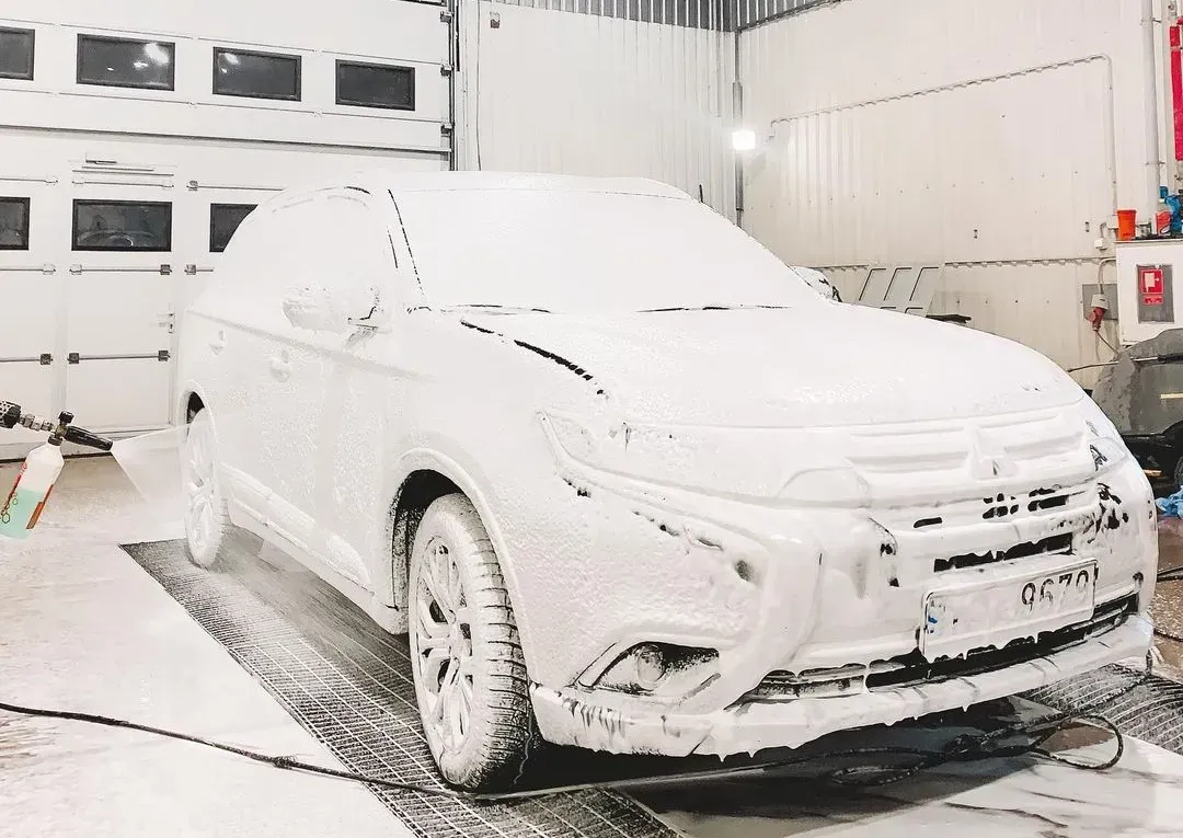 Balta mašīna garāžā ir pārklāta ar putām.