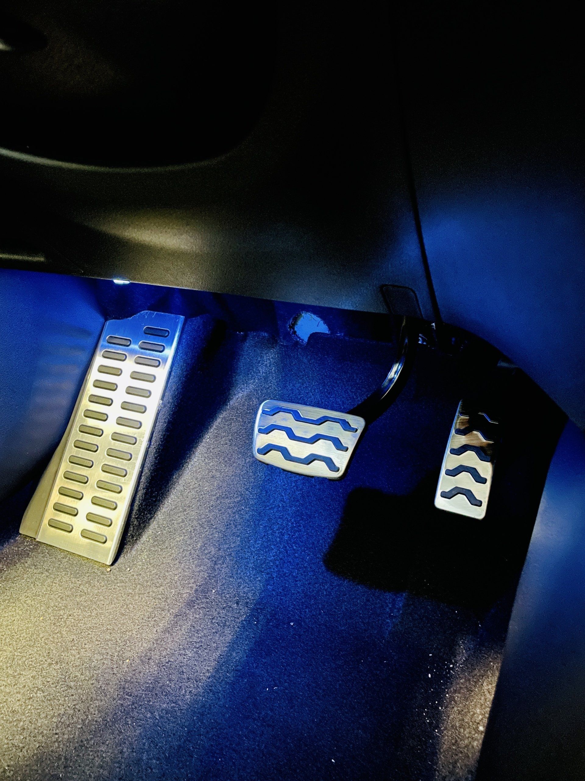 Tuvplāns automašīnas pedāļiem ar zilām gaismām aiz tiem