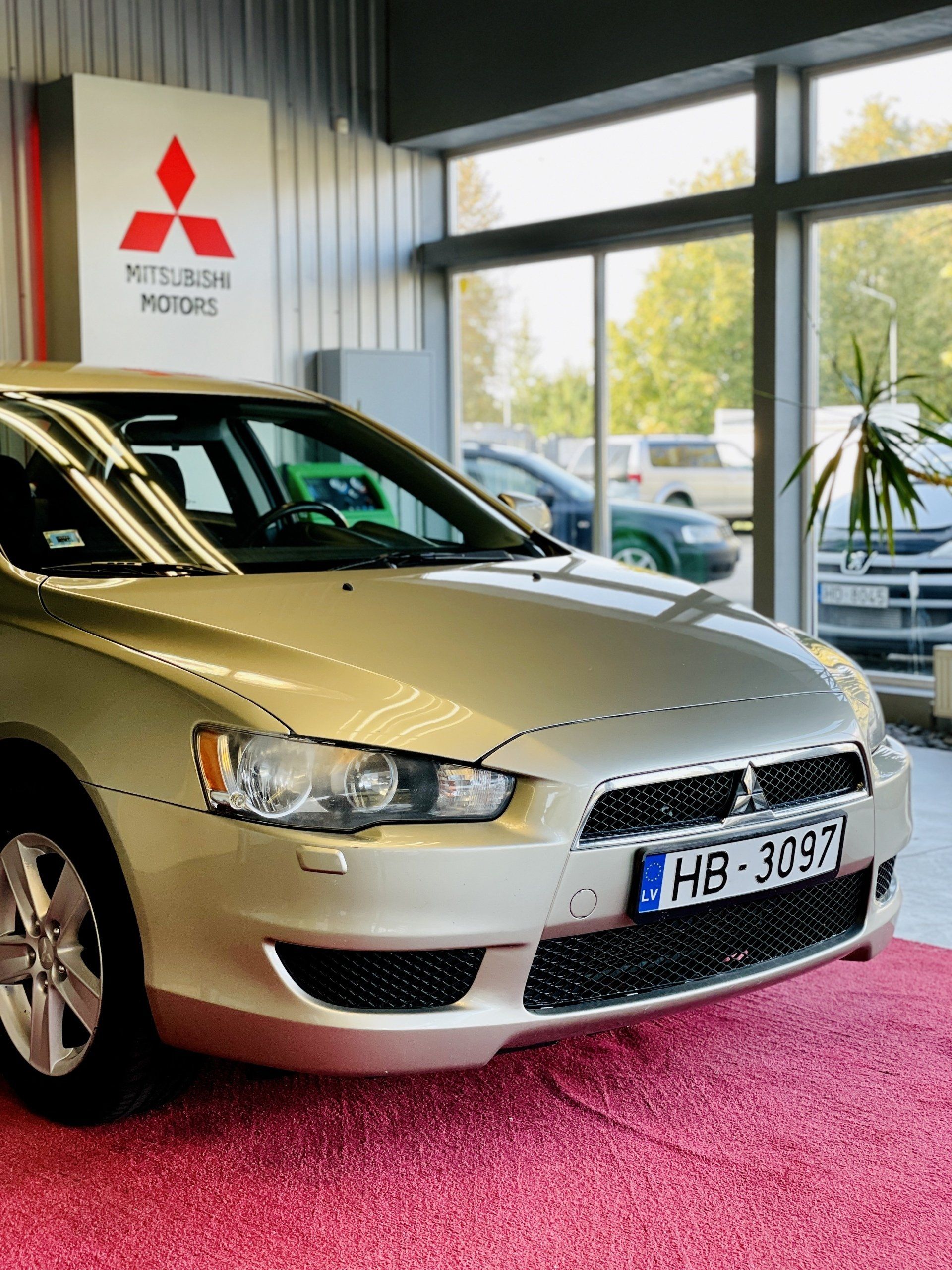 Sudrabainā mitsubishi automašīna ir novietota salonā.