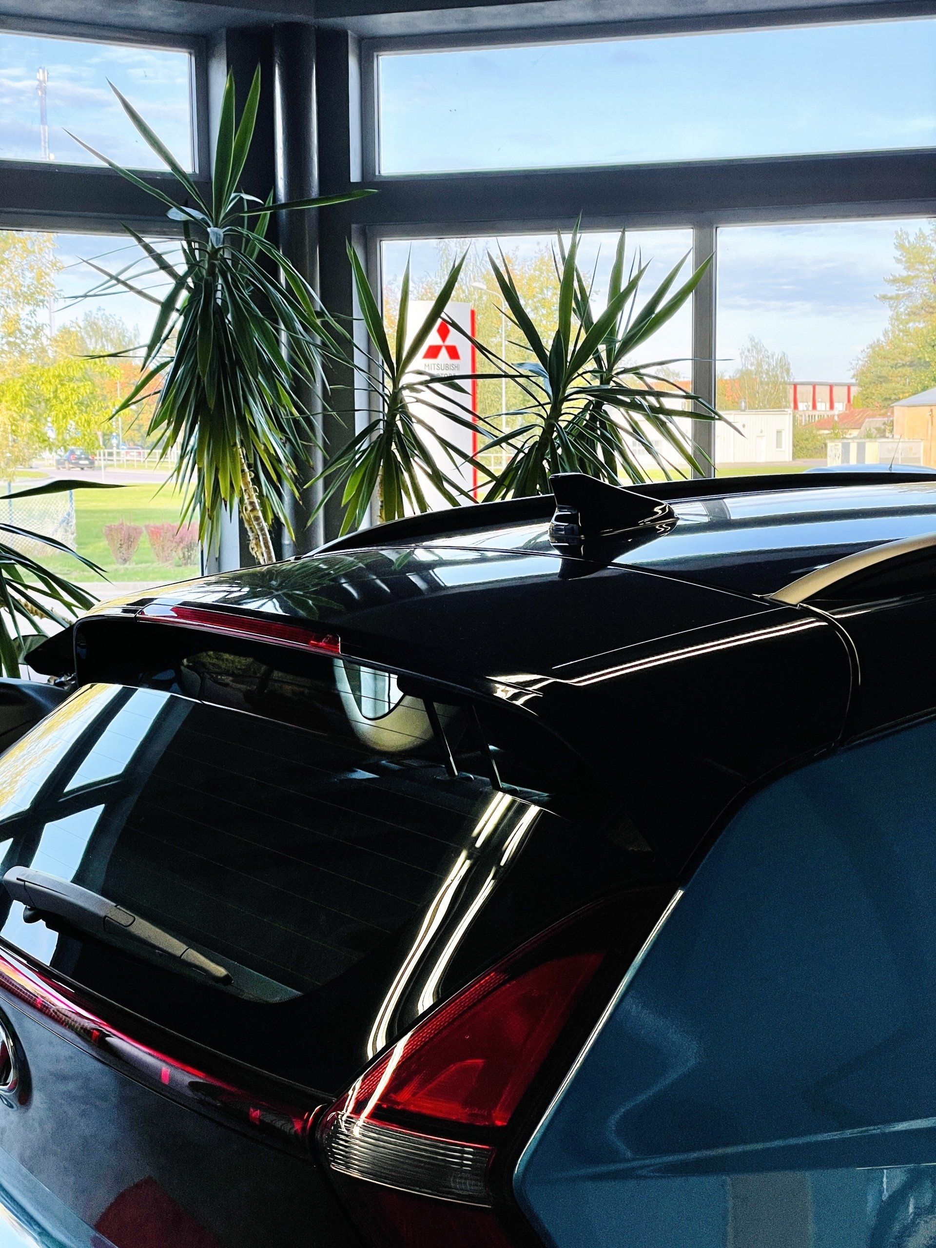 Pie loga stāv melna mašīna