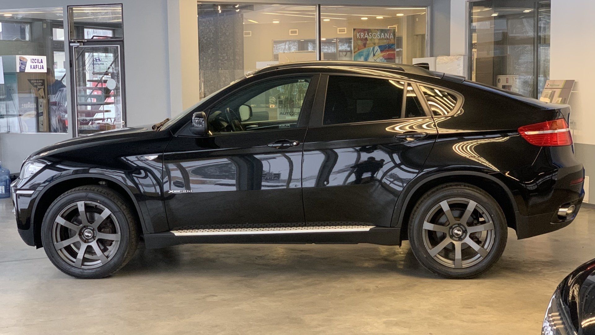Melns bmw x6 stāv salonā.