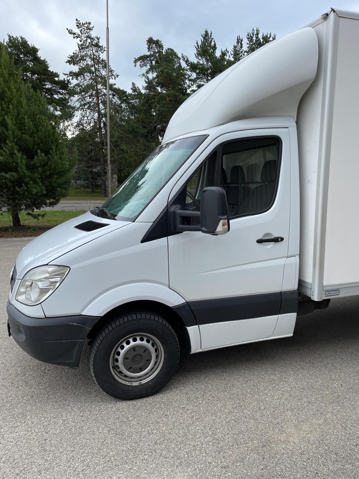 Ceļa malā stāv balts furgons.