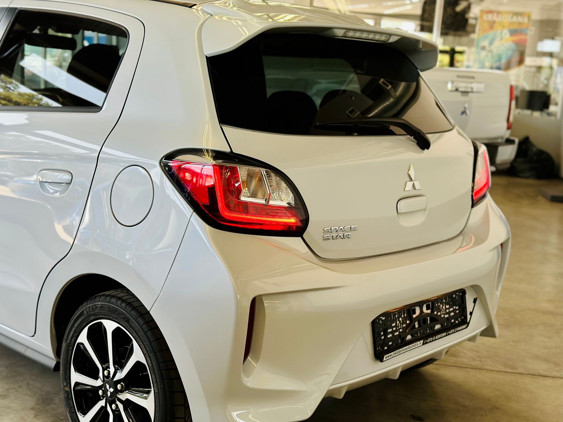 Balts mitsubishi mirage hečbeks ir novietots garāžā.