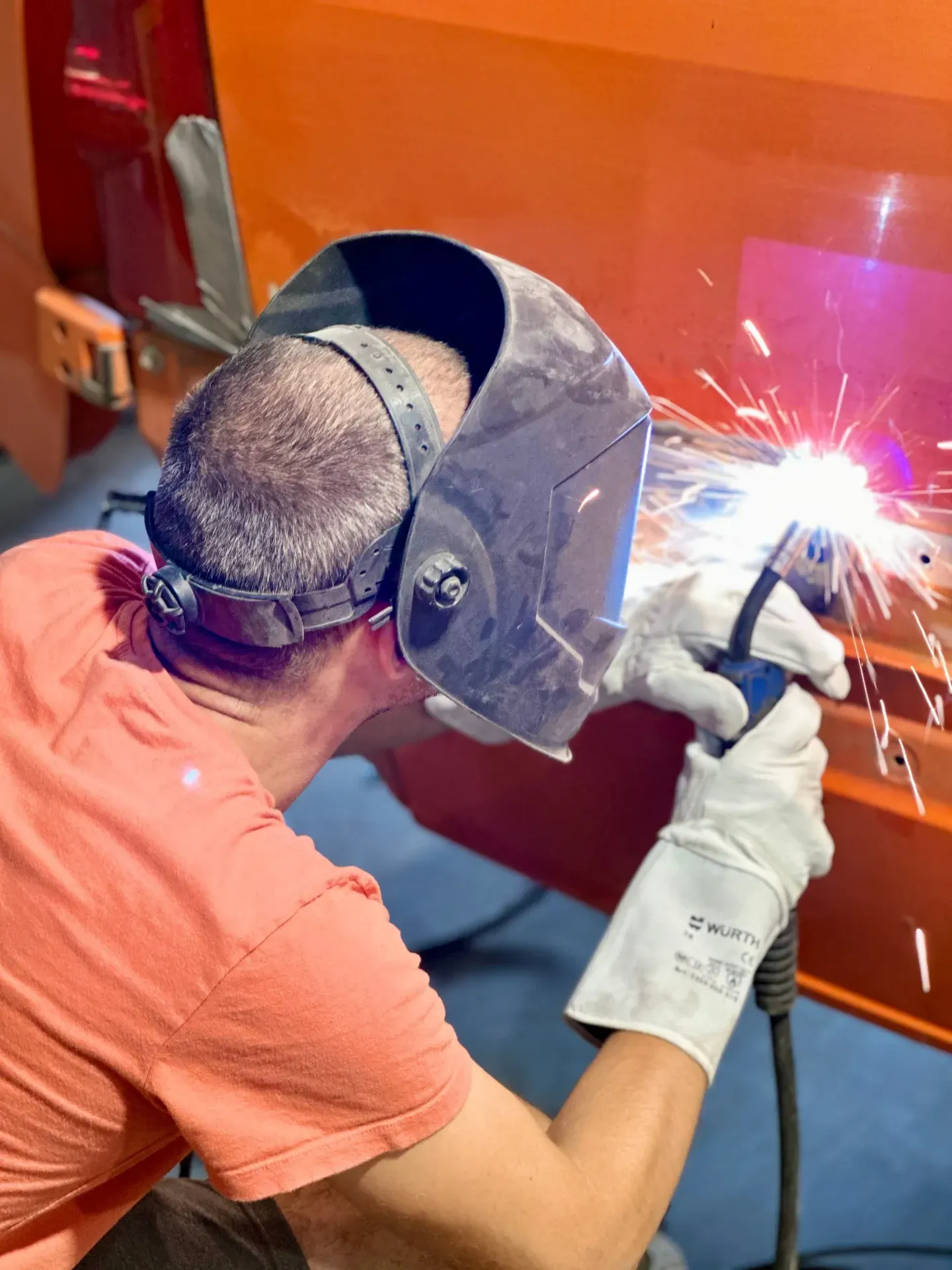 Vīrietis, kas valkā metināšanas masku, metina metāla gabalu.