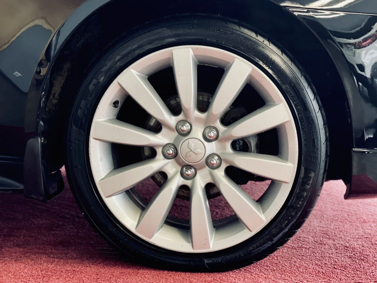 Tuvplāns ar automašīnas riteni uz sarkanā paklāja