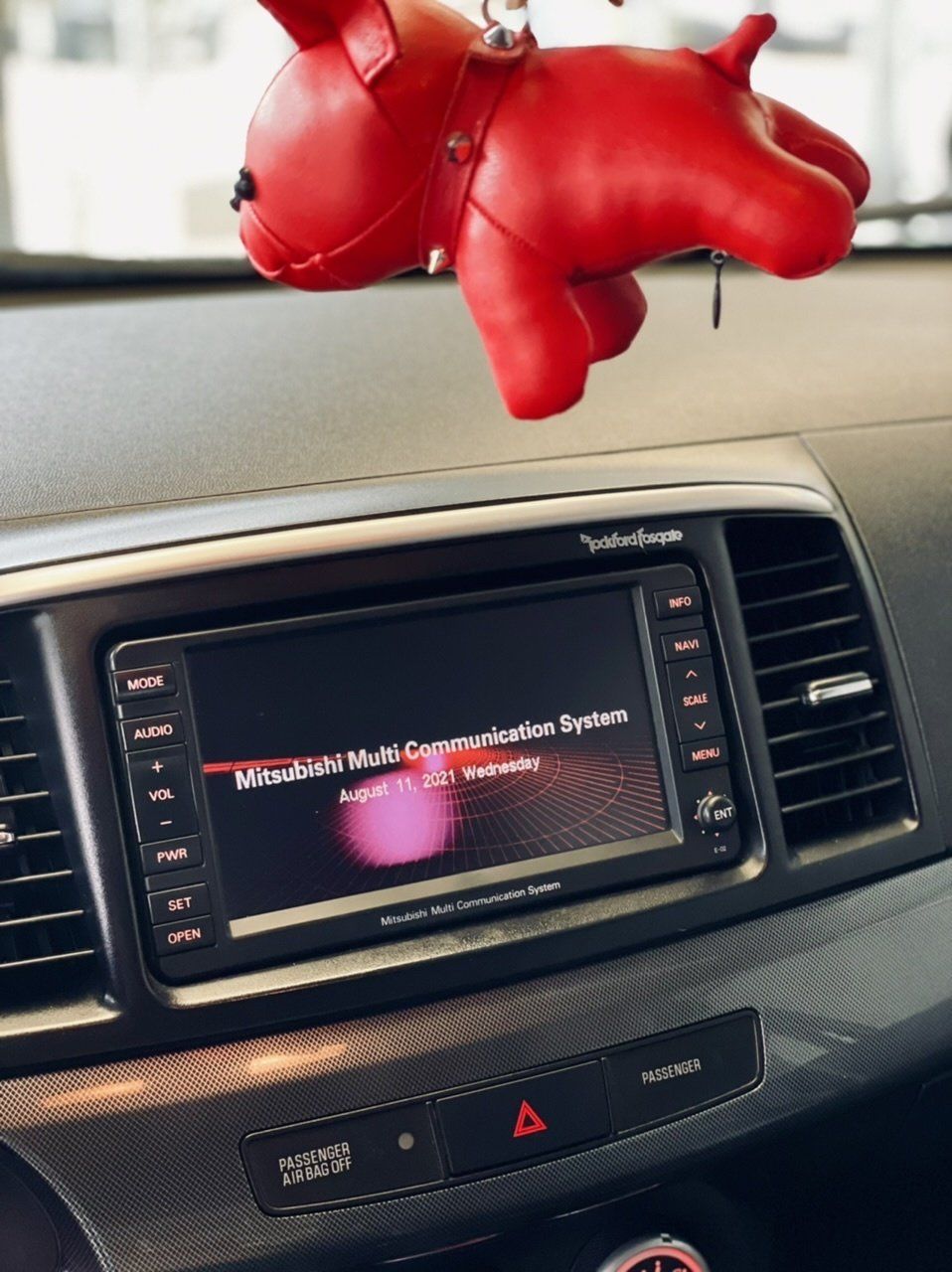 Pie automašīnas atpakaļskata spoguļa karājās sarkans suns izbāzts