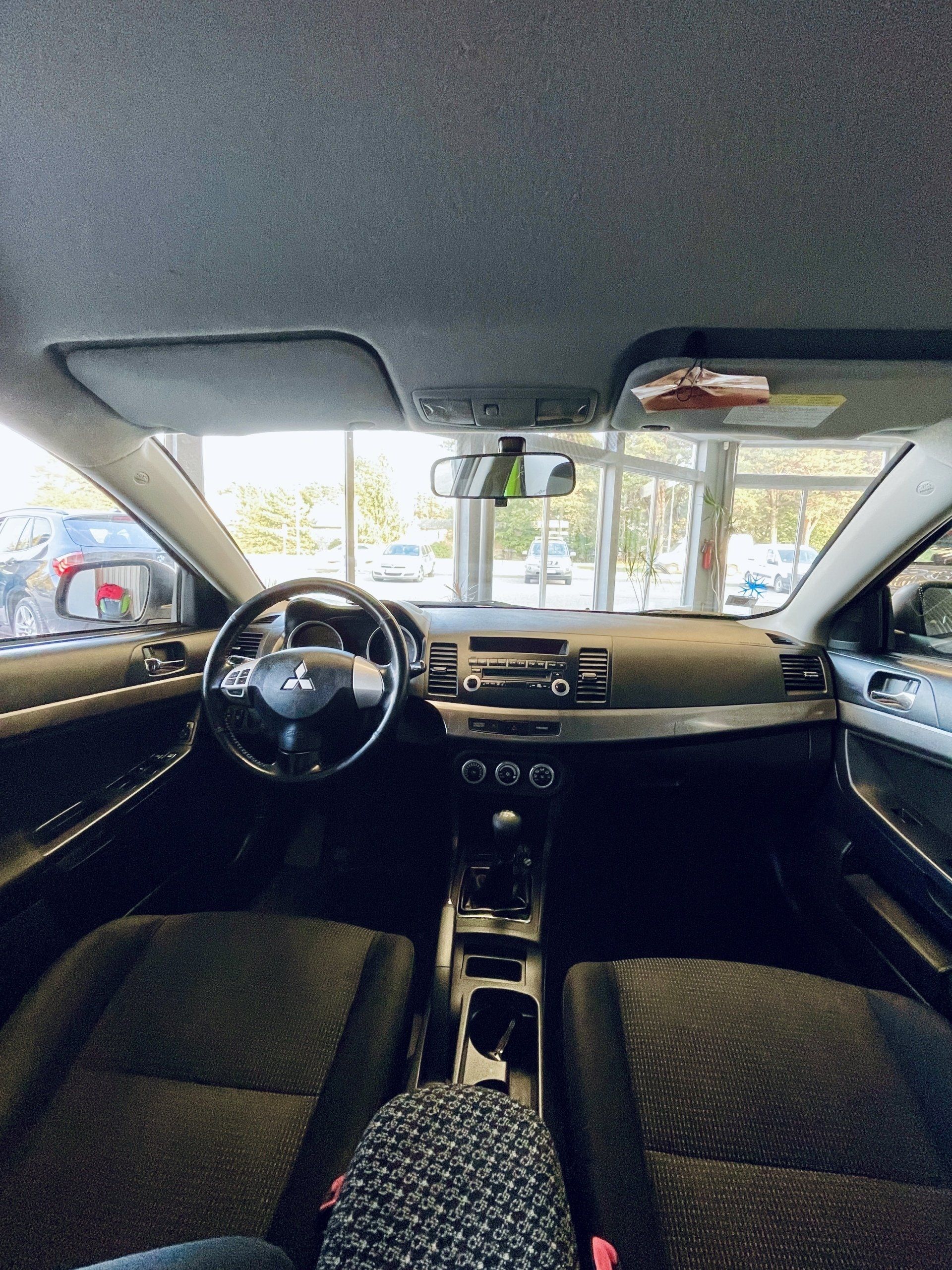 Automašīnas iekšpuse ar stūri un instrumentu paneli.