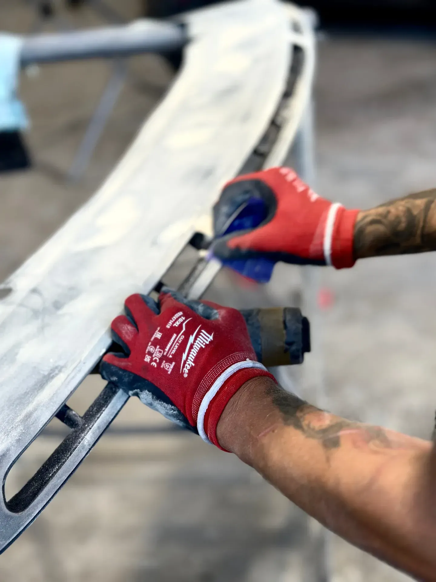 Vīrietis sarkanos milvoki cimdos strādā pie metāla gabala