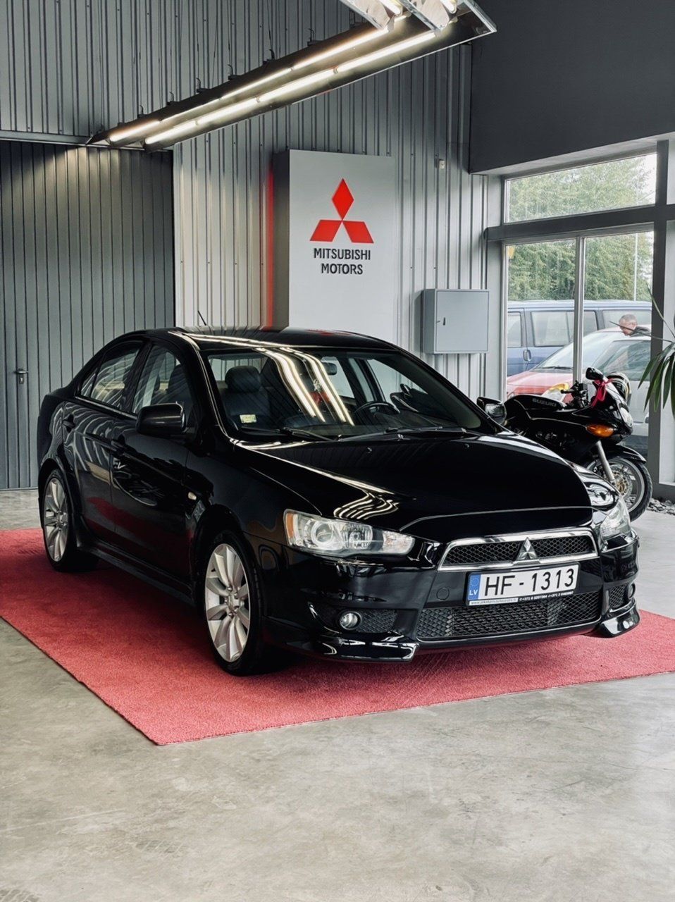Auto salonā stāv melns mitsubishi.