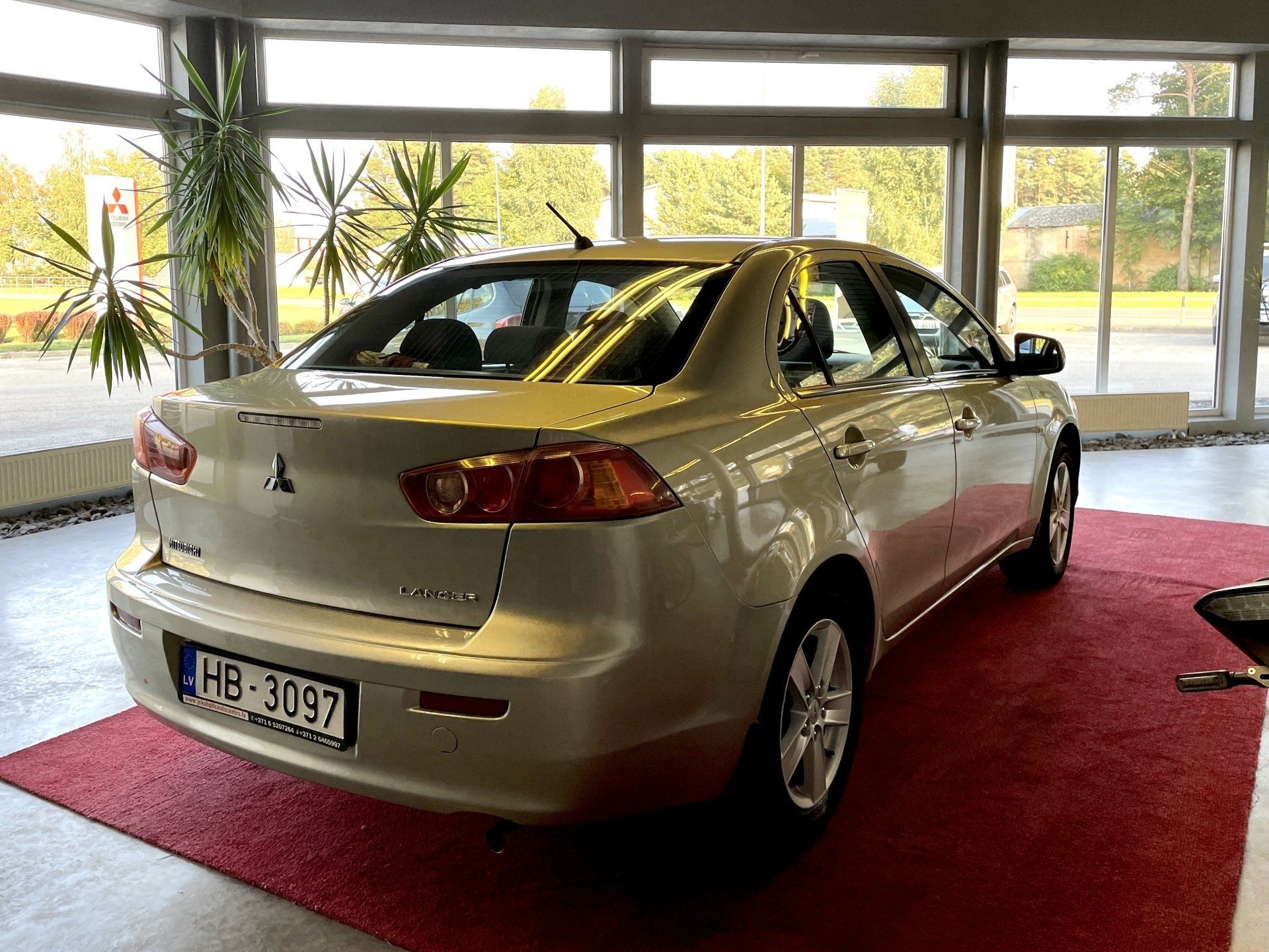 Sudraba automašīna sēž uz sarkanā paklāja izstāžu zālē.