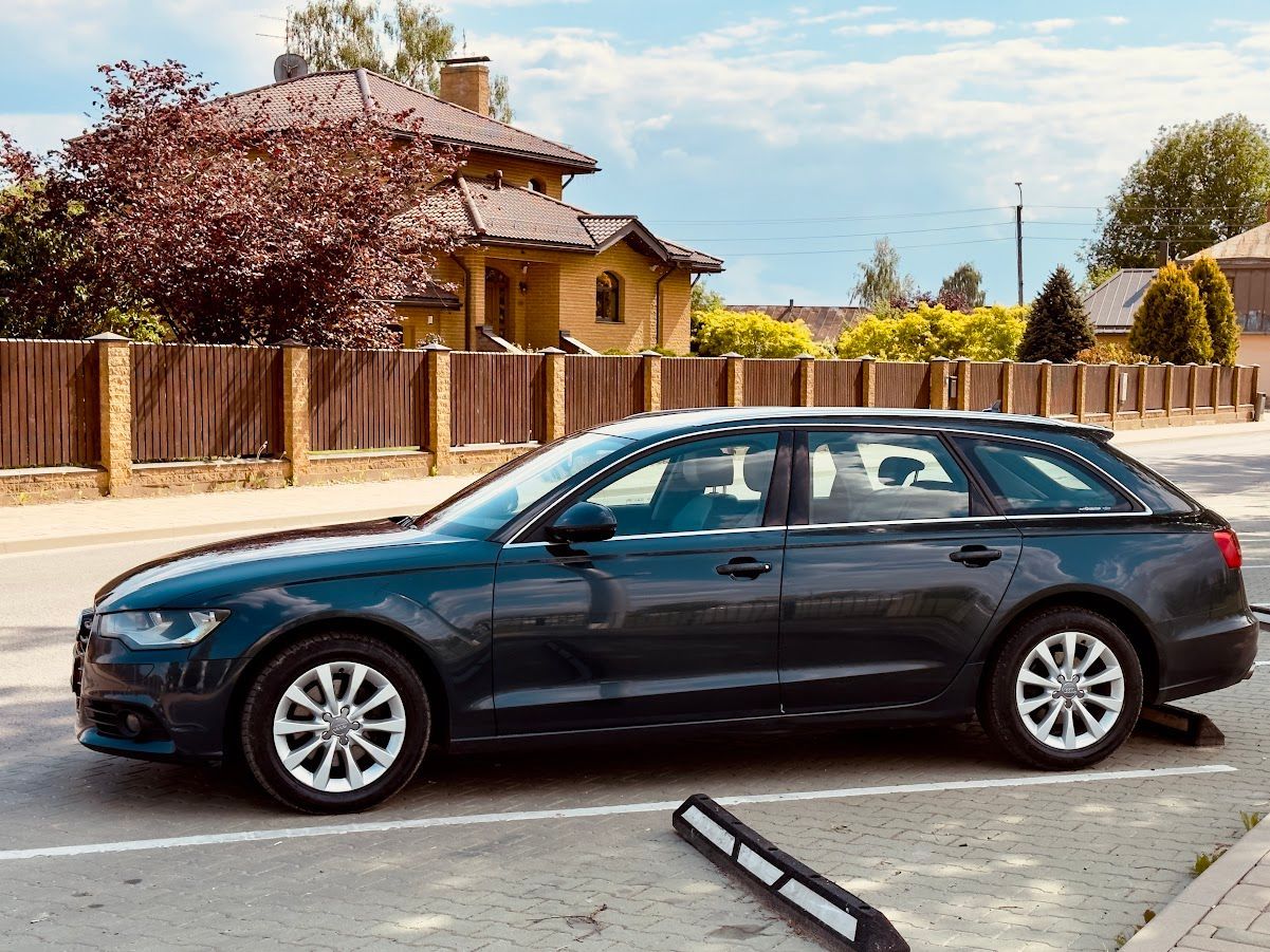 Ceļa malā pie mājas stāv zila mašīna.