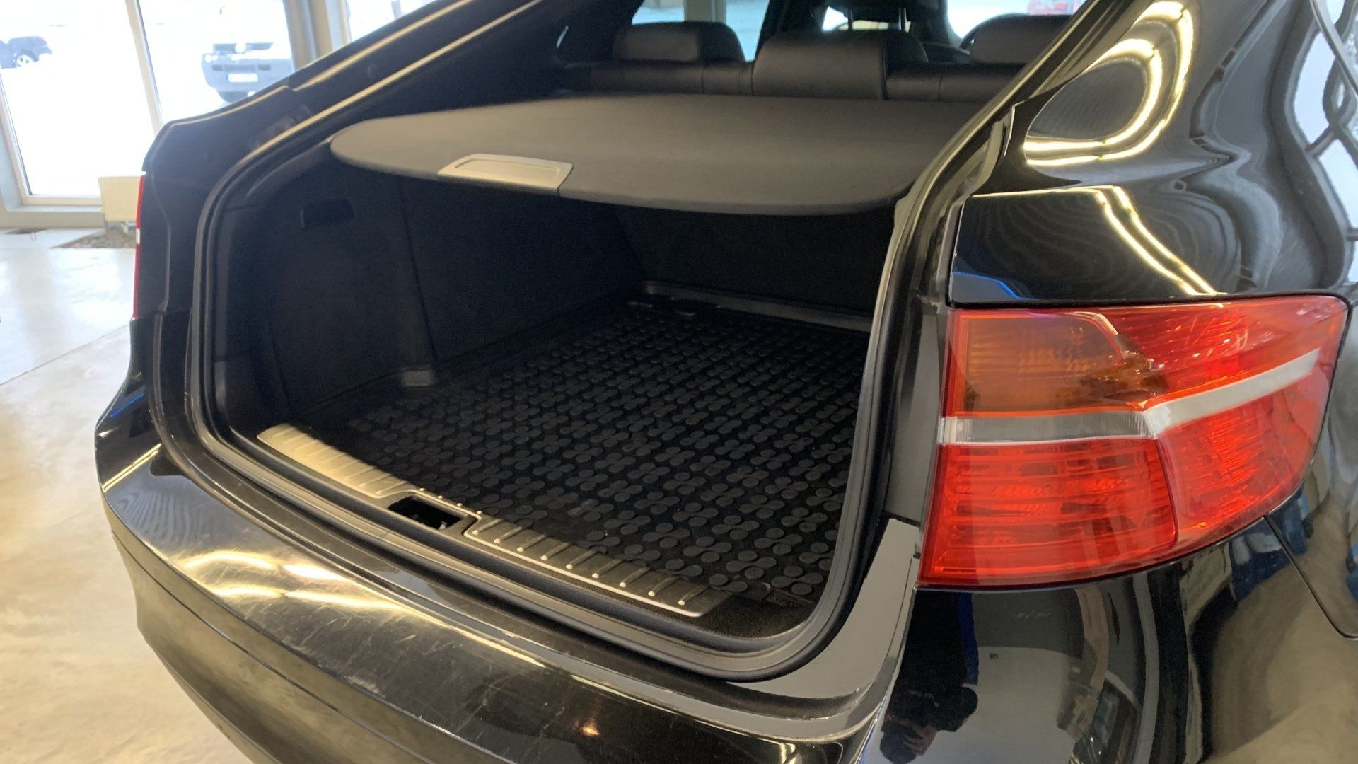 Aizmugure melnai automašīnai ar atvērtu bagāžnieku.