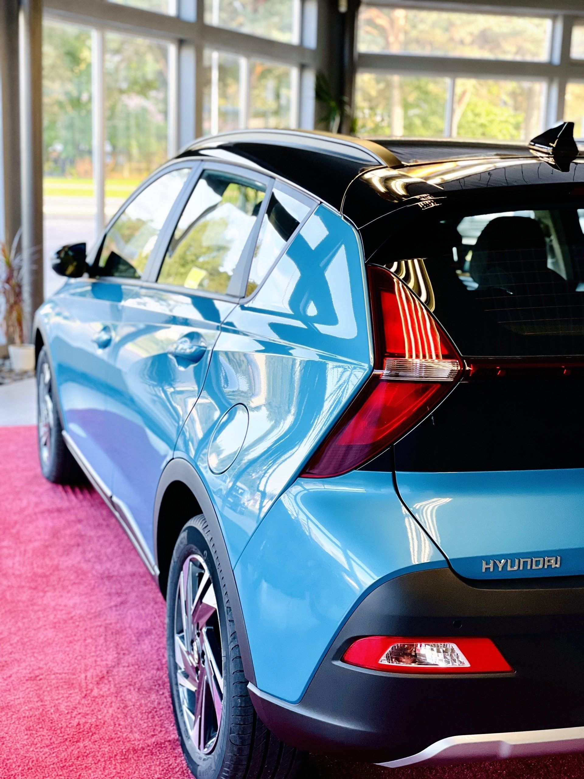 Zila hyundai automašīna ir novietota uz sarkanā paklāja izstāžu zālē.