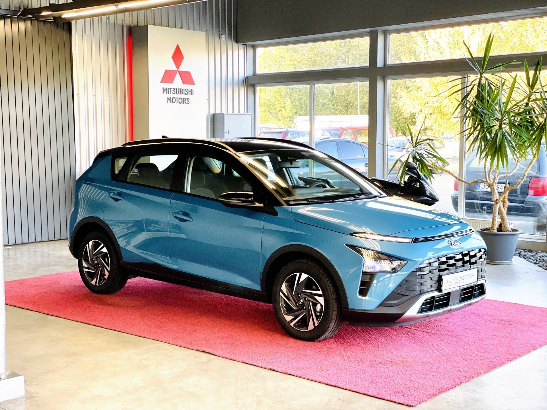 Zila mašīna ir novietota uz rozā paklāja salonā.