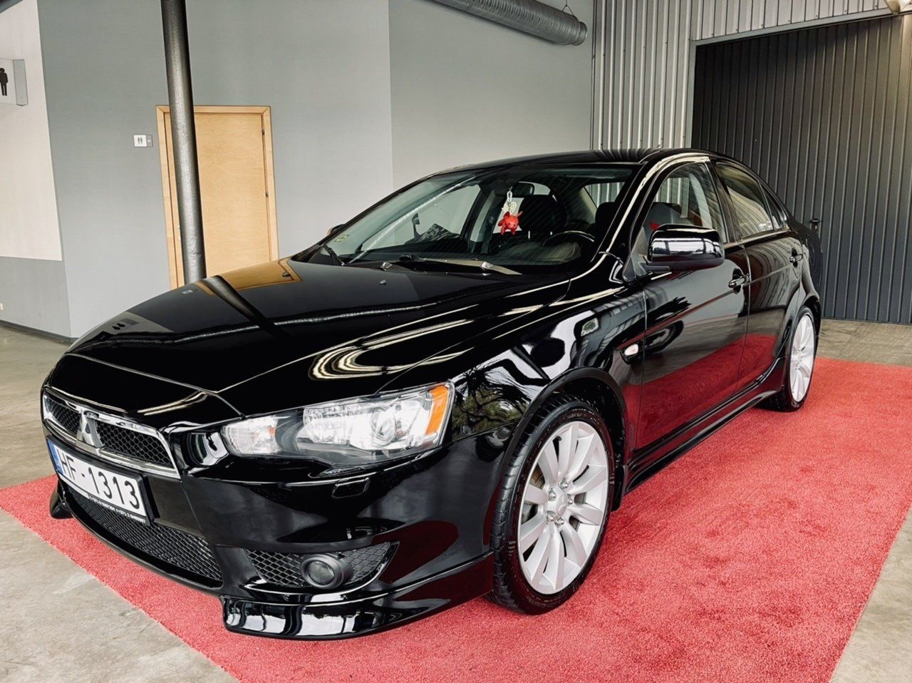 Melna automašīna ir novietota uz sarkanā paklāja salonā.