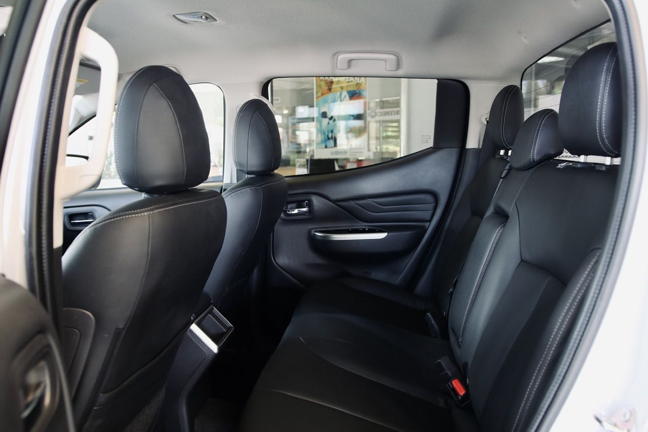 Baltas kravas automašīnas aizmugurējais sēdeklis ar melniem ādas sēdekļiem.