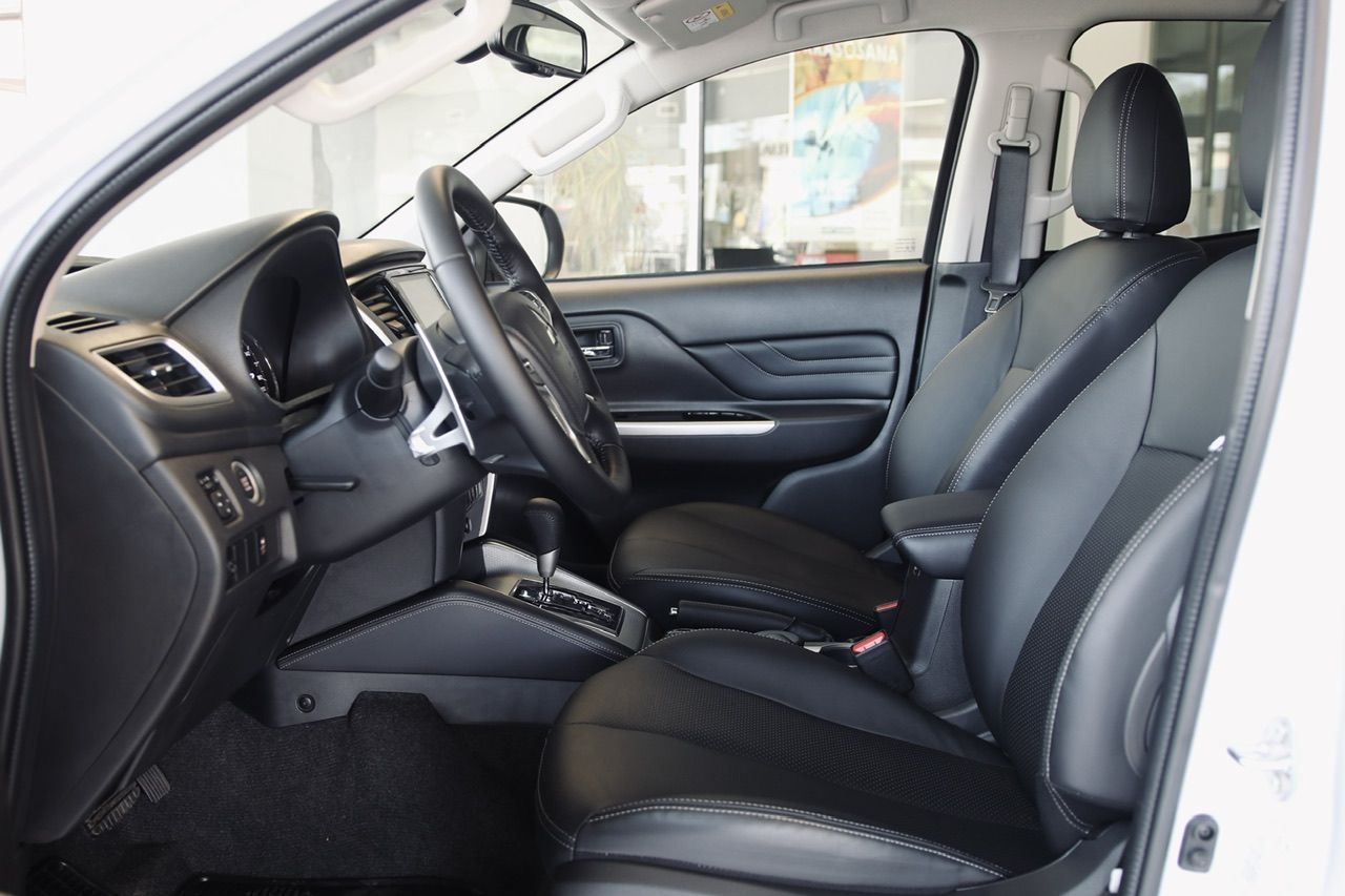 Baltas automašīnas salons ar melniem sēdekļiem un stūri.