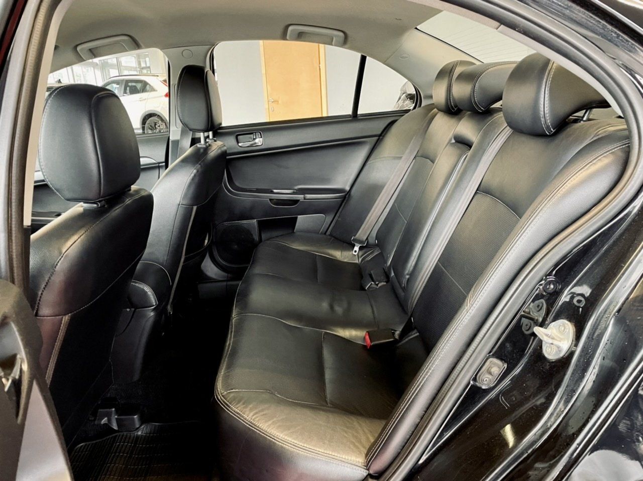 Melnas automašīnas aizmugurējais sēdeklis ar ādas sēdekļiem.