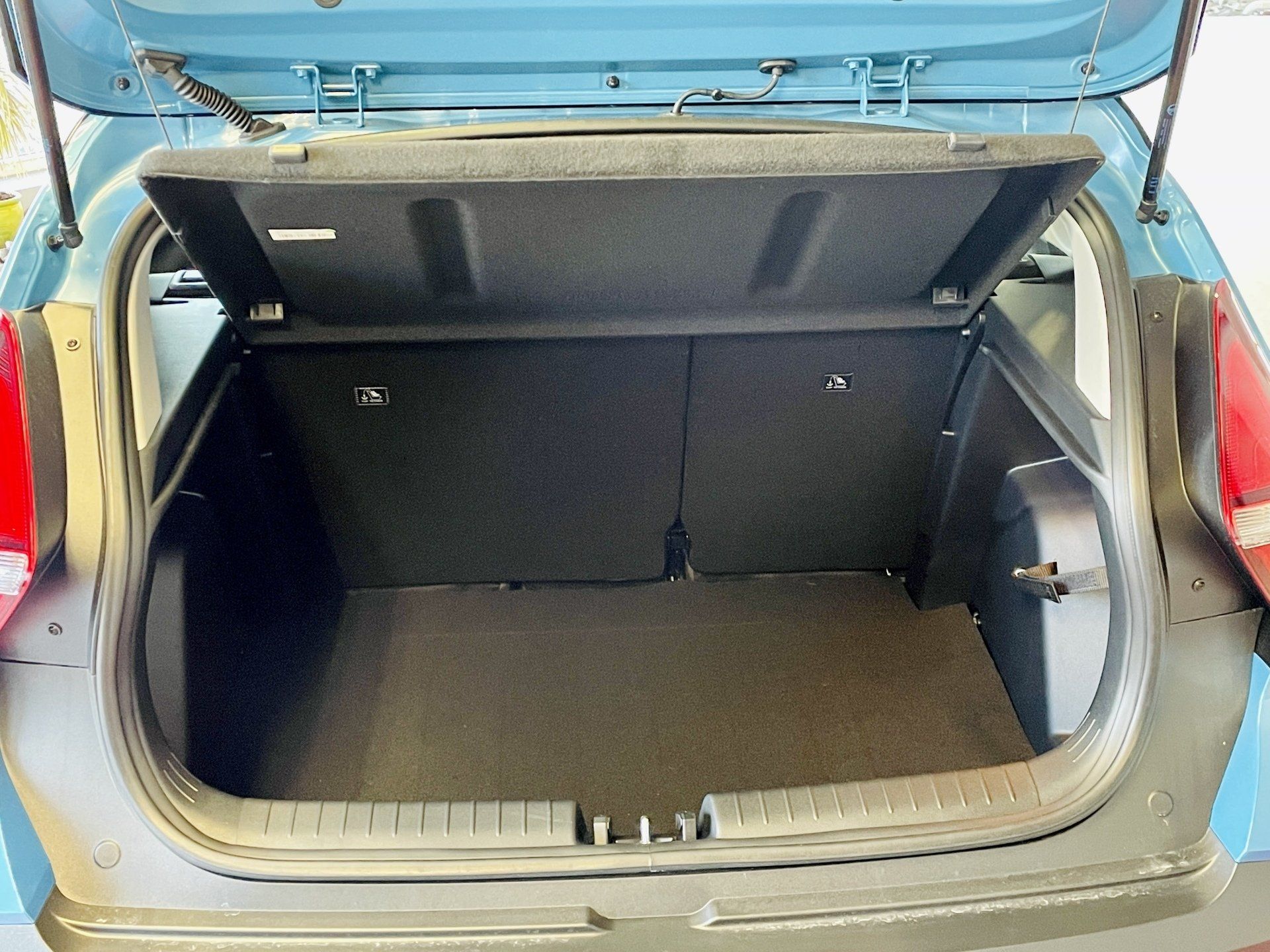 Zilas automašīnas aizmugure ar atvērtu bagāžnieku