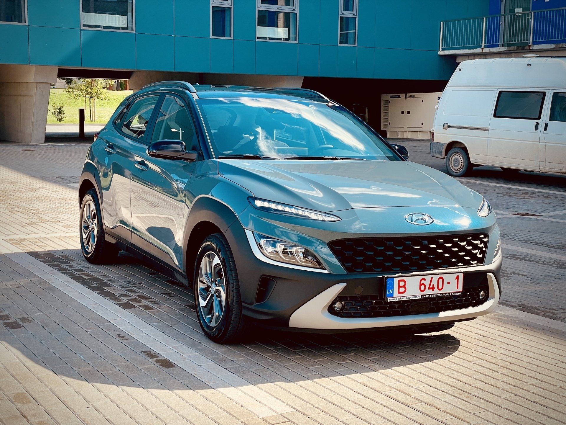 Automašīna ir novietota stāvvietā pie ēkas.