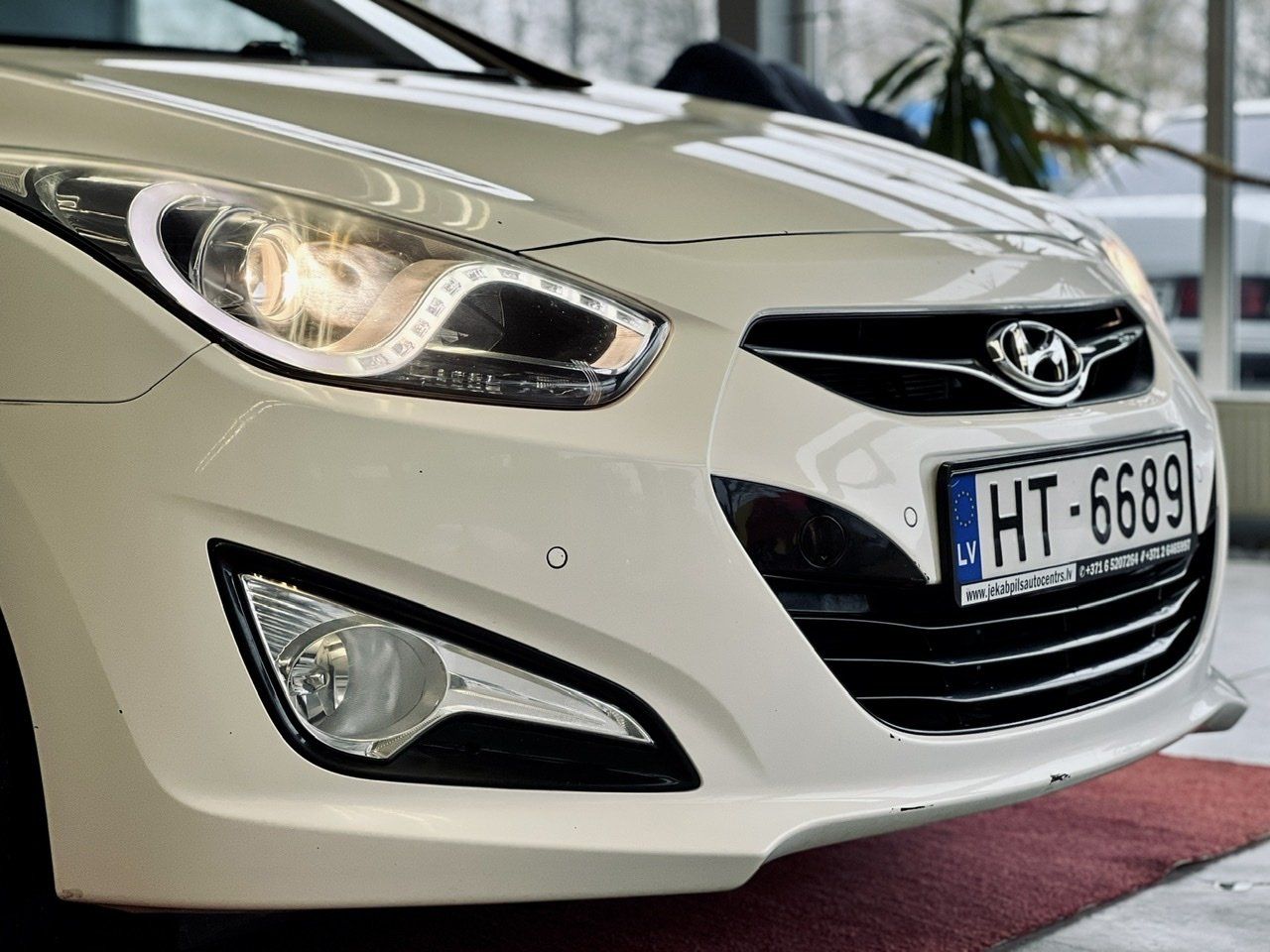 Balta automašīna ar numura zīmi, kurā rakstīts ht 6689