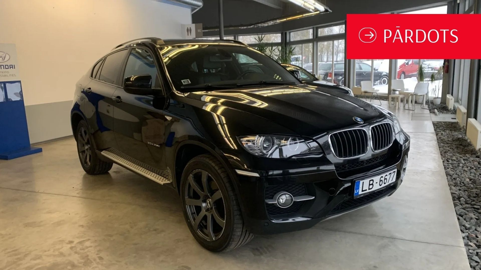 Melns bmw x6 stāv salonā.