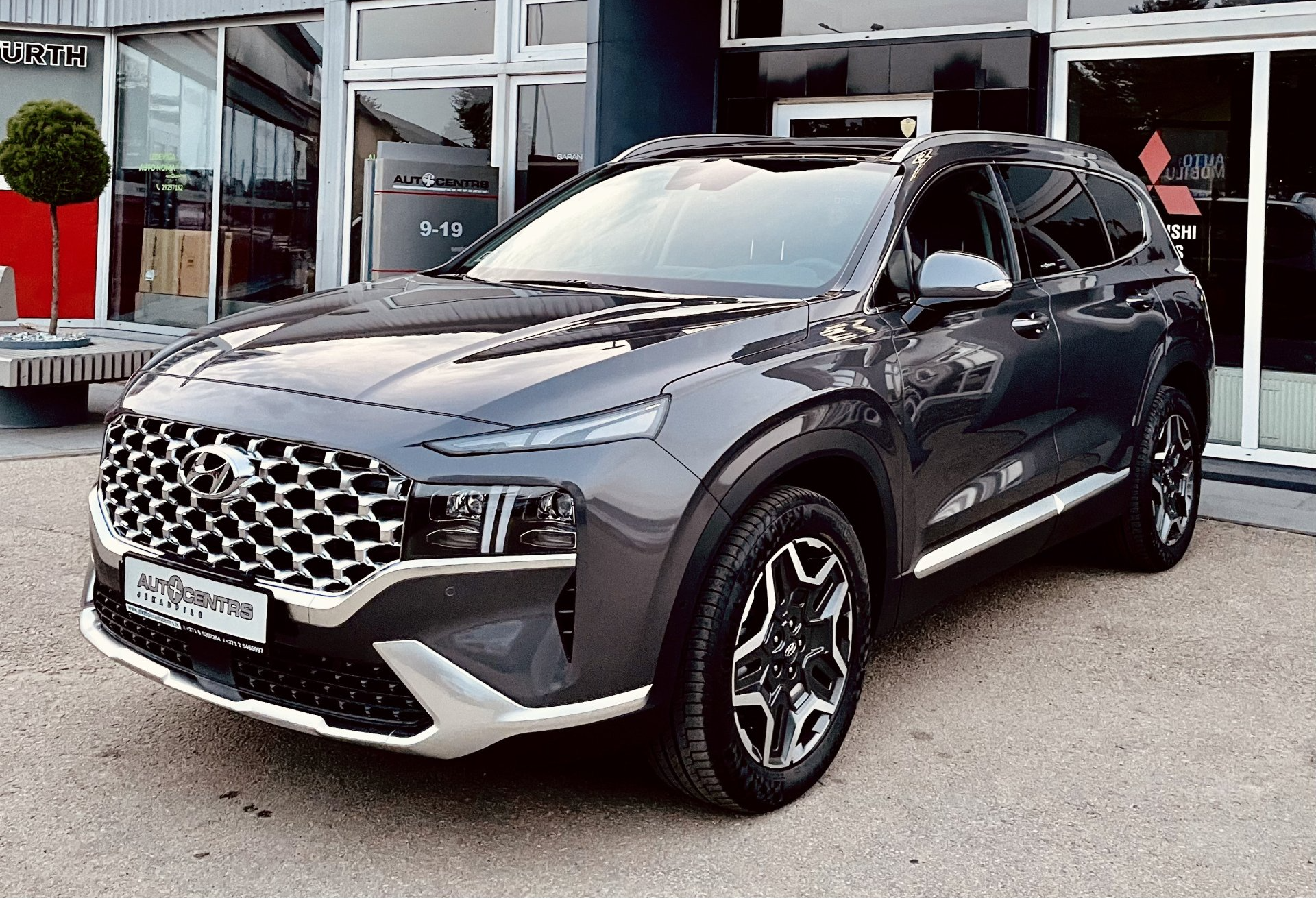 Pelēks apvidus auto ir novietots kādas ēkas priekšā.