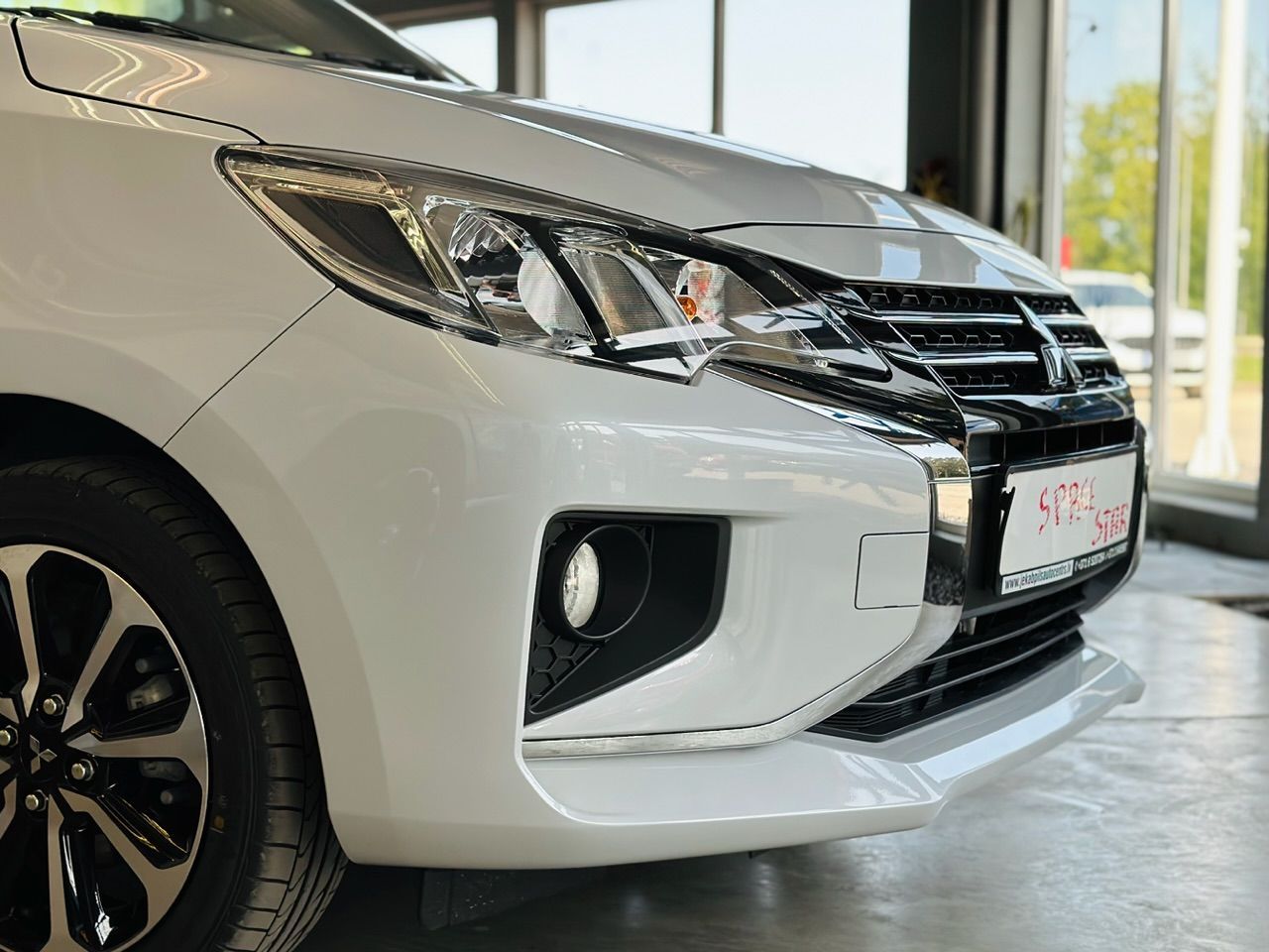 Salonā stāv balta mašīna ar melniem riteņiem.