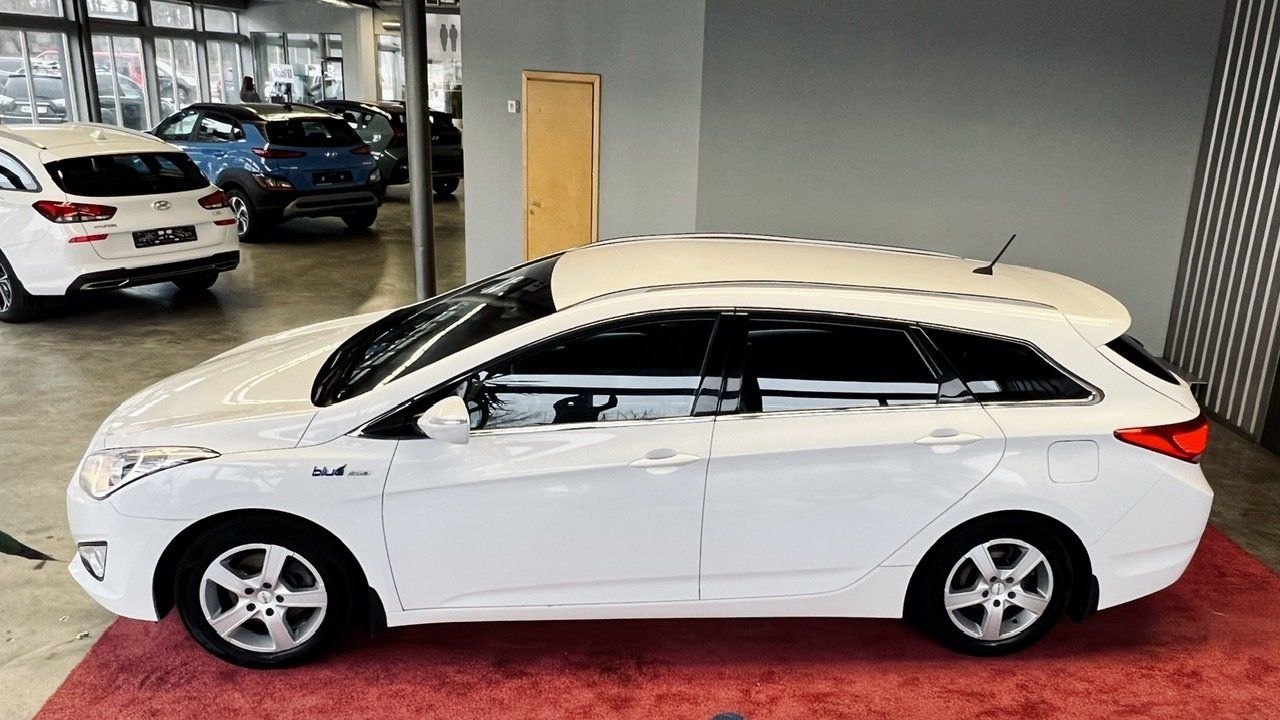 Balta automašīna ir novietota salonā pie citām automašīnām.