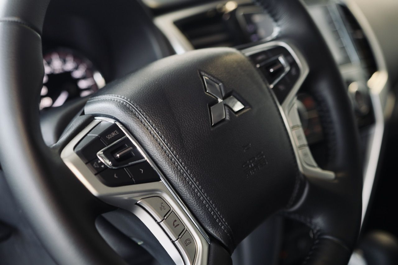 Stūres rata tuvplāns ar Mitsubishi logotipu uz tā.