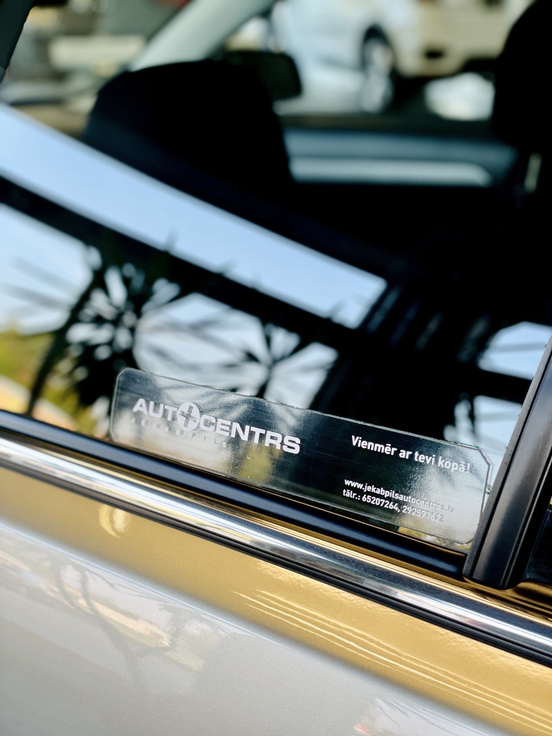 Automašīna ar uzlīmi uz loga, kurā rakstīts auto centrs