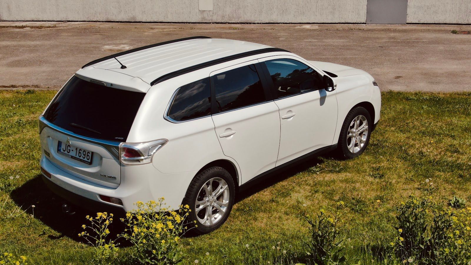 Zāliena laukā stāv balts apvidus auto.